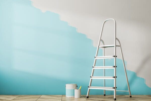 Interior Paint Smells: What Causes Them and How to Get Rid of Them Fast in Phoenix and Tucson Homes 4 Empty room interior with a wooden floor and a half painted blue wall. A ladder and tins of paint.