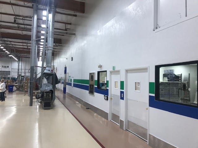 Arizona Painting Company's skilled industrial painters providing durable protective coatings for machinery and structures, enhancing both longevity and aesthetics. Painters painting an industrial room with blue and green stripes against a white wall.