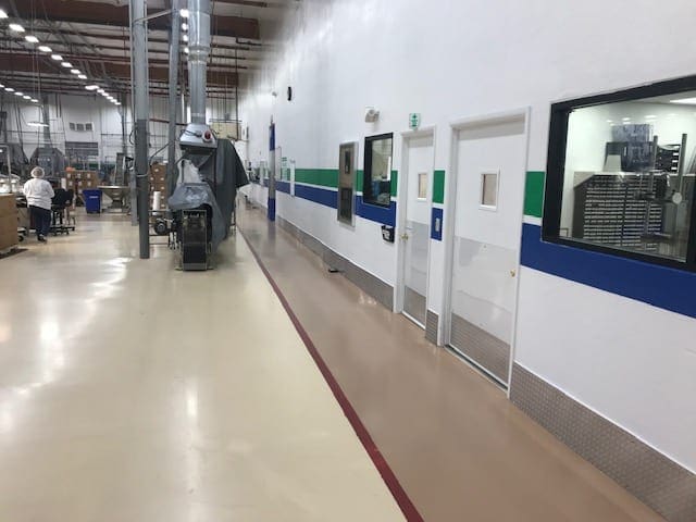 Arizona Painting Company's skilled industrial painters providing durable protective coatings for machinery and structures, enhancing both longevity and aesthetics. Industrial room with white walls painted with a blue and green stripe.