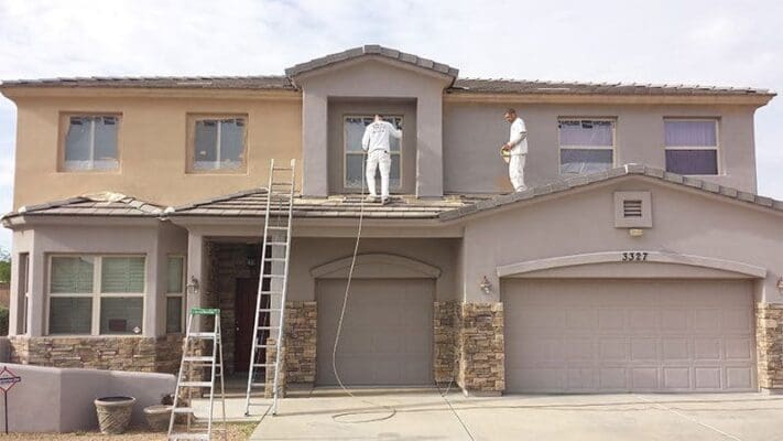 Residential exterior prepared for painting by Arizona Painting Company: A "before" image showcasing the home's surroundings covered with tarps, ladders, and supplies arranged, indicating the meticulous preparations for a transformative paint job.