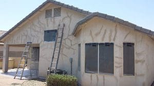 Residential exterior prepared for painting by Arizona Painting Company: A "before" image showcasing the home's surroundings covered with tarps, ladders, and supplies arranged, indicating the meticulous preparations for a transformative paint job.