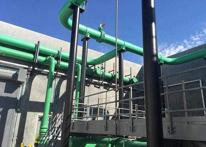 Arizona Painting Company's skilled industrial painters providing durable protective coatings for machinery and structures, enhancing both longevity and aesthetics. Green painted industrial machinery being shown.